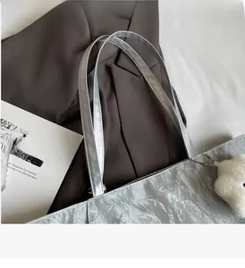 Detail of silver pleated tote bag with metallic finish and plush star charm on side