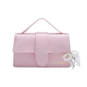 Pink faux leather shoulder bag with gold logo and pearl bow charm on white background