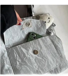 Close-up of silver tote bag with crinkle texture, butterfly buckle and interior storage