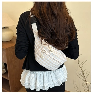 Detail of plaid canvas saddle bag showing crescent shape and metal triangle zipper pulls