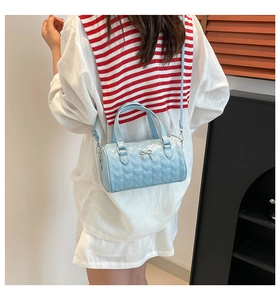 Detail of light blue cylinder bag showing heart-shaped texture and silver bow accent
