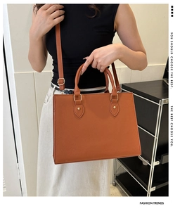 Detailed view of caramel tote bag featuring textured leather and golden metal buckles