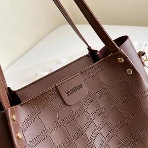 Detailaufnahme der braunen Kunstleder-Tasche mit Krokodilprägung und Metallnieten-Verzierung