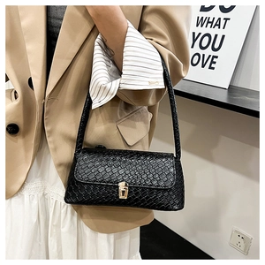 Detail of black woven texture handbag with golden square lock on beige blazer outfit