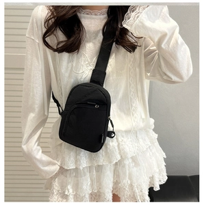 Détail du sac de poitrine en nylon noir minimaliste avec bandoulière et fermetures