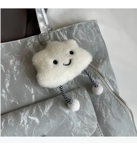 Close-up of a white fluffy cloud pendant with striped legs hanging on a silver bag