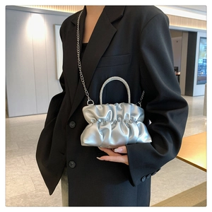 Detailed shot of silver ruched handbag with rhinestone handle and metal chain strap