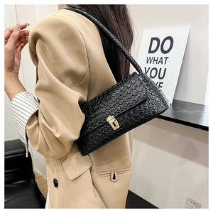 Detailed view of black woven texture baguette bag with an elegant golden clasp
