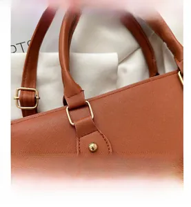 Close-up of brown Saffiano leather texture with golden metal hardware and neat stitching