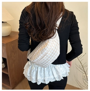 Rear view of a model wearing the brown plaid crossbody chest bag with white strap