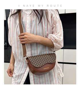 Detail of a brown half-moon saddle bag featuring geometric dot print and wide strap