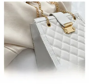 Detail shot of the white quilted shoulder bag with gold chain and precise side stitching