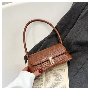 Detail of brown woven texture faux leather baguette bag with a gold metal clasp