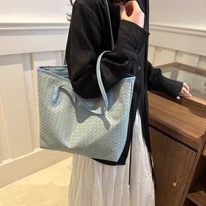 Light blue woven tote bag with slim handles shown on a model for daily commute outfit