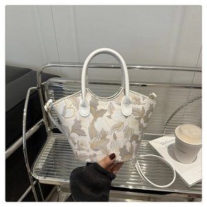 Macro shot of white floral shoulder bag with round handle and metal zipper detail