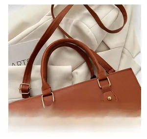 Detail view of brown Saffiano PU leather handbag with golden hardware and round handles