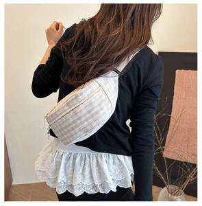 Close-up of checkered canvas saddle bag with metal zippers and woven strap details