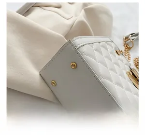 Detail view of white quilted shoulder bag base featuring two golden protective metal studs