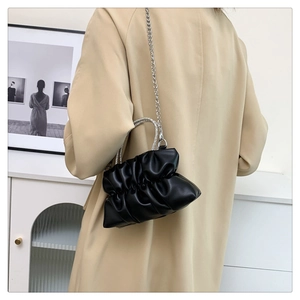 Detail of black pleated cloud bag with rhinestone handle and silver chain on model