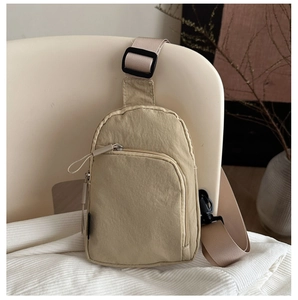 Détail du sac bandoulière minimaliste en nylon beige avec poches zippées sur tissu