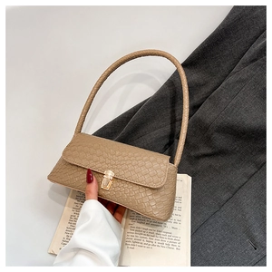 Detail of khaki woven baguette bag with a gold metal clasp and interior compartment space