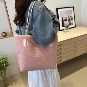 Pink woven tote bag featuring a leather patch detail and long shoulder strap for women
