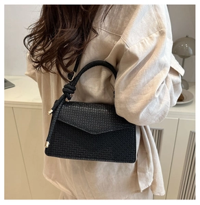 Détail du sac à carreaux noir avec poignée nouée et finitions dorées sur mannequin épuré