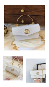 Detail of white crocodile pattern flap and golden M logo with circular metal handle