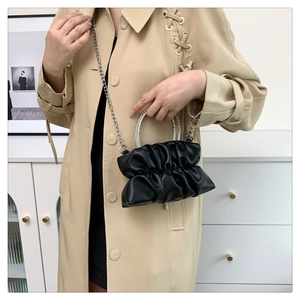 Detail of black pleated cloud bag featuring sparkling rhinestone handles and silver chain