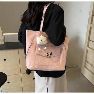 Pink canvas tote bag with butterfly metal buckle and white cloud plush charm on a model