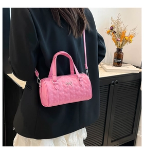 Pink heart quilted cylinder bag with bow detail held by model in casual lifestyle setting