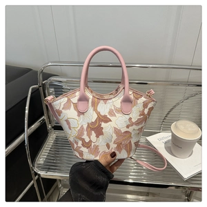 Detail of pink floral handbag with leather handles and detachable strap on a sofa