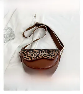 Detail of leopard print saddle bag with wide shoulder strap and gold lettering