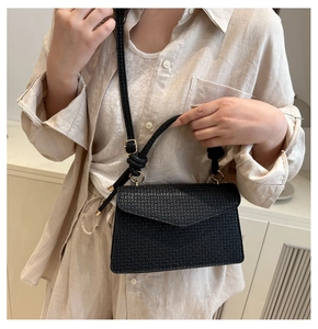 Détail du sac bandoulière noir tressé avec boucle dorée et poignée supérieure nouée