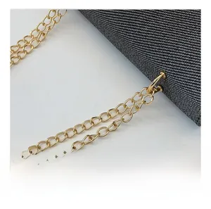 Detalle de la correa de cadena dorada en un bolso de mezclilla gris con diseño retro