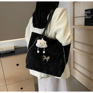 Detail of black pleated tote bag featuring a silver butterfly buckle and cloud charm