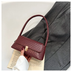 Macro detail of wine red crocodile embossed leather baguette bag with golden buckle