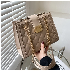 Detail of beige quilted shoulder bag featuring gold chain strap and metal twist lock