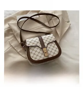 Detailed view of the vintage lock closure on a brown saddle bag next to a smartphone