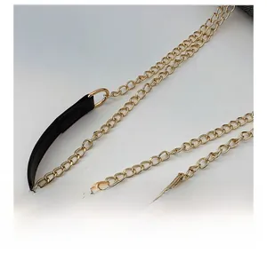 Primer plano de la cadena de metal dorado con detalles de costura en cuero negro