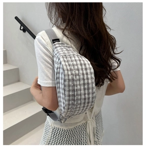 Detailed view of gray checkered chest bag with adjustable strap on model's shoulder