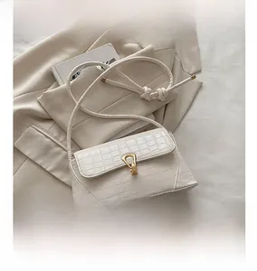 White crocodile pattern bag detail with gold metal clasp and size comparison to phone