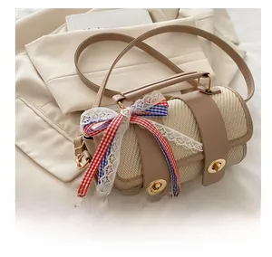 Close-up of beige woven pillow bag with leather trim and decorative plaid bow details