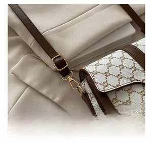 Close-up of golden metal buckle and textured leather pattern on a saddle bag