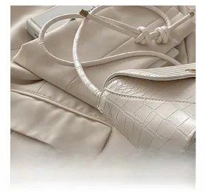 Detail view of white crocodile pattern shoulder bag with unique knotted strap design