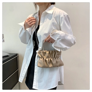 Detail of beige pleated cloud bag with sparkling rhinestone handle and chain strap