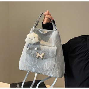 Close-up of silver wrinkled tote bag featuring a metallic butterfly buckle and cloud charm