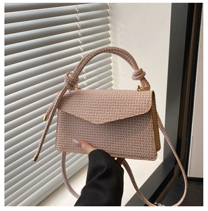 Détail d'un sac bandoulière à motifs géométriques avec poignée nouée et finitions dorées
