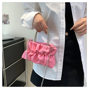 Close-up of pink pleated cloud bag featuring rhinestone-encrusted handles and metal chain