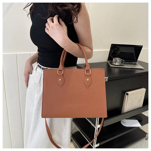Detailed view of a tan business tote bag being held by a model in an office setting